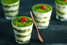 four small desserts with green and red toppings on the top one is filled with raspberries