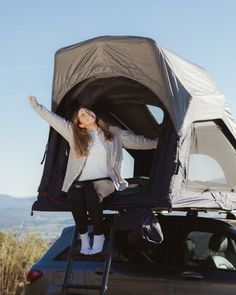 a woman sitting on the roof of a car