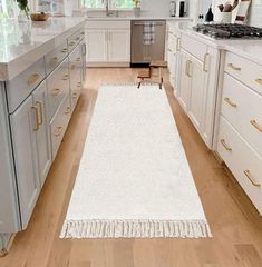 a white rug in the middle of a kitchen with gold handles and drawers on both sides