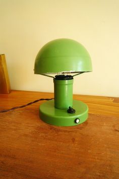 a green lamp sitting on top of a wooden table