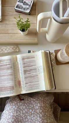 an open book sitting on top of a table next to a cup and coffee mug