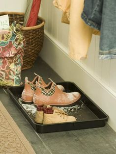 two pairs of shoes are sitting on a tray in front of a coat rack and clothes