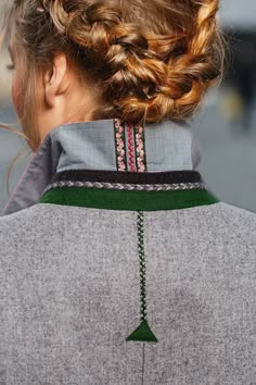 the back of a woman's head with braids in her hair, wearing a gray sweater