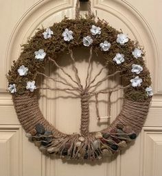 a wreath with flowers and leaves hanging on the front door to decorate it for someone's special occasion