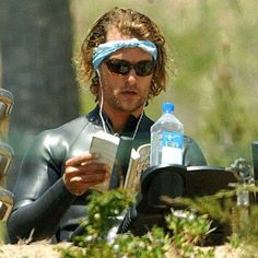 a man sitting on the ground wearing headphones and holding a water bottle in his hand