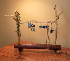 a tree branch with jewelry hanging from it's sides on top of a wooden table