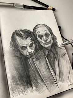 a drawing of two clowns with their faces painted black and white, on a piece of paper