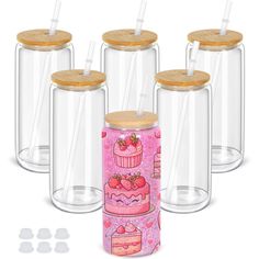 four glass jars with wooden lids and straws on the top one has a pink cake design