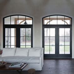 a living room with two large windows and a white couch in front of the door