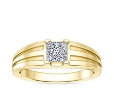 a yellow gold ring with a princess cut diamond in the center, set on a white background