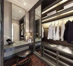 a walk in closet with clothes on hangers and a stool next to the mirror