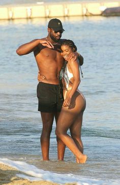 a man and woman are standing in the water at the beach with their arms around each other