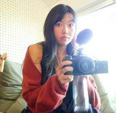 a woman sitting on a couch holding a camera