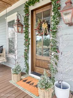 a porch decorated for christmas with wreaths and potted plants