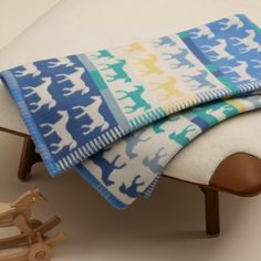 a blanket is folded on top of a wooden toy horse and bench in front of a white wall