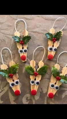 four wooden reindeer head ornaments with holly leaves on them