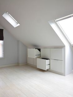 an empty room with two skylights and white cupboards in the middle of it