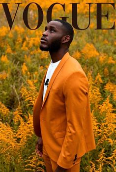 a man in an orange suit standing in front of yellow flowers