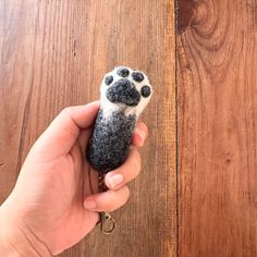 a hand holding a tiny animal toy on top of a wooden floor