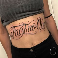 a woman's stomach with the word tattoo on her lower side ribcage