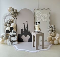 a cake and balloons are displayed in front of a backdrop for a mickey mouse themed birthday party