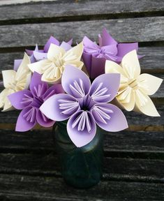 a vase filled with paper flowers sitting on top of a wooden bench