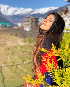 a woman with long hair is looking up at the sky and mountains in the background