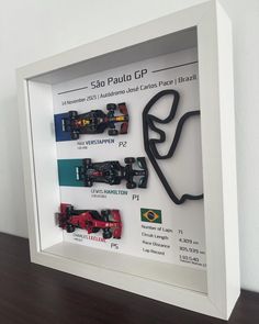 a display case with various race cars in it on a wooden table next to a white wall