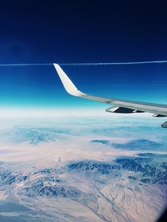 the wing of an airplane flying over mountains