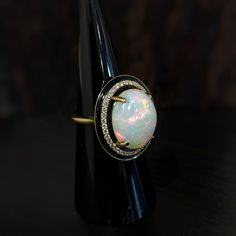 This statement ring features a 7.49 carat oval opal gemstone of size 16x12 mm with a halo of natural earth mined diamonds and black enamel detail, all set in solid 14K gold. This ring can be a beautiful October birthstone gift for your loved ones! This ring is made with solid 14K Gold and natural Earth mined SI / G-H diamonds. As listed, this ring is ready to ship. If you're interested in purchasing this setting with a different center stone please message us! Modern Oval Opal Ring For Formal Occasions, Oval Cabochon Opal Ring In Fine Jewelry, Oval Cabochon Opal Ring Fine Jewelry, Fine Jewelry Oval Cabochon Opal Ring, Luxury Polished Opal Ring, Oval Cabochon, Luxury Opal Ring With Oval Cabochon And Polished Finish, Luxury Opal Ring Oval Cabochon For Gift, Luxury Opal Ring With Cabochon Cut, Modern Oval Cabochon Opal Ring As Gift