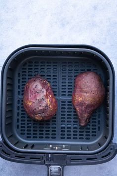 two pieces of meat sitting on top of an air fryer pan next to each other