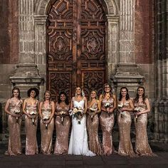 a group of women standing next to each other in front of a wooden door holding bouquets