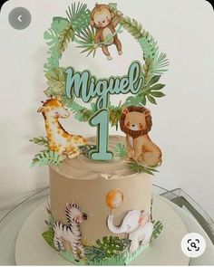 a birthday cake decorated with jungle animals and the number one on it's top