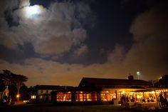 the full moon shines brightly in the night sky above an outdoor market with people standing outside