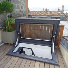 an open roof window on top of a wooden deck next to a potted plant