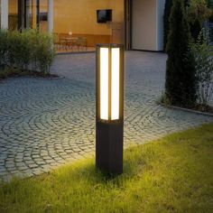 an outdoor light on the ground in front of a house