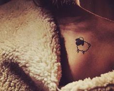 a woman with a small tattoo on her chest and the word sheep written in black ink