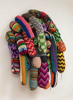 a pile of colorful knitted objects hanging on a wall