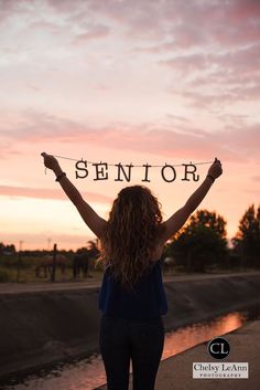 a woman holding up a sign with the word senior on it in front of her