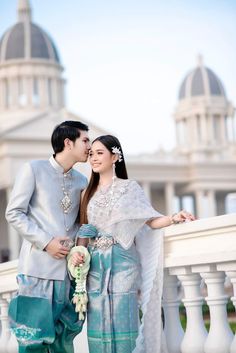 a man and woman standing next to each other in front of a white building with columns