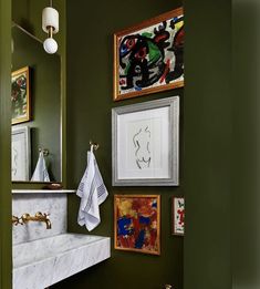 a bathroom with green walls and pictures on the wall