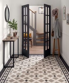 an open door leading into a hallway with black and white tiles on the flooring