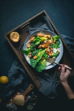 a white plate topped with broccoli and chicken on top of a wooden tray