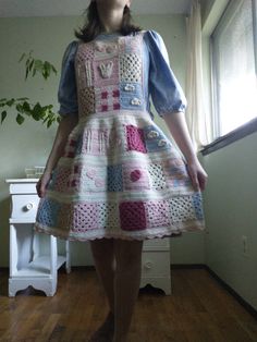 a woman standing in front of a window wearing a crocheted dress and hat