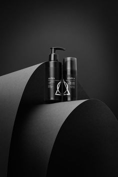 two shampoos sitting next to each other on top of a black object in the dark