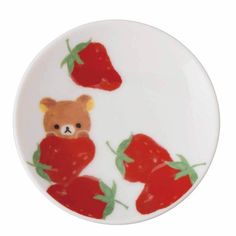 a white plate with two red strawberries and a brown teddy bear on the side