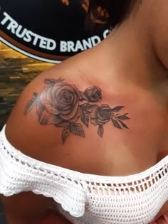 a woman with a rose tattoo on her upper back shoulder and right arm, in front of a sign that reads trusted brands