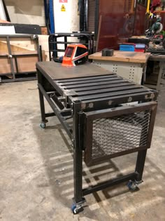 a metal table sitting on top of a hard wood floor next to a workbench