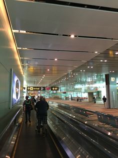 people are walking down an escalator at the airport