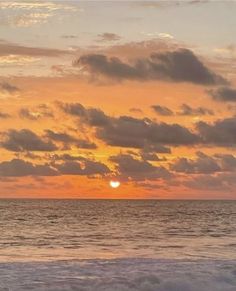 the sun is setting over the ocean with clouds